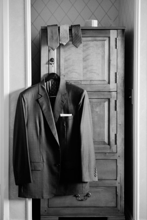 Tuxedo jacket hanging with a selection of ties.