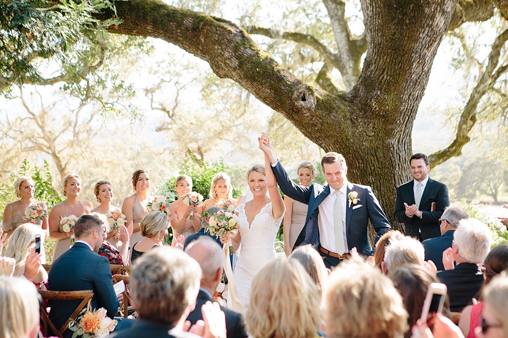 bride and groom walk down aisle arm raised in celebration at Beltane Ranch wedding by michelle walker photography