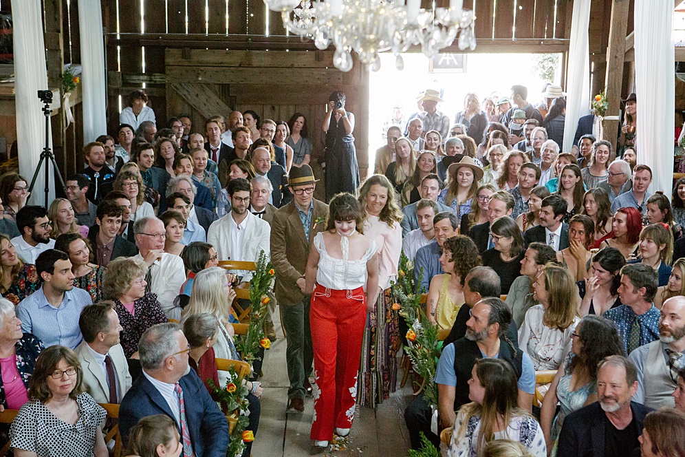 bride in vintage red pants walking down the aisle at Five Springs Ranch wedding by michelle walker photography