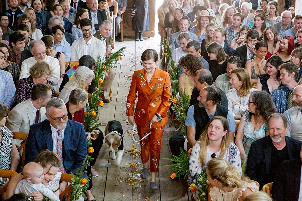 maid of honor in custom orange suit and a puppy ring bearer walking down the aisle at Five Springs Ranch wedding by michelle walker photography