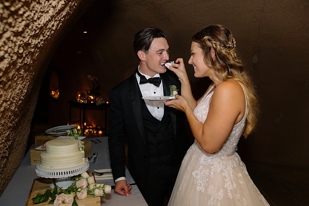 bride and groom eat cake at calistoga ranch wedding by michelle walker photography