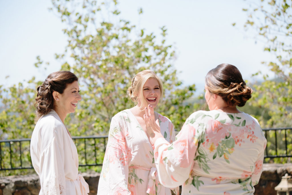 Bride and her bridesmaids in matching pink robes getting ready for the wedding.